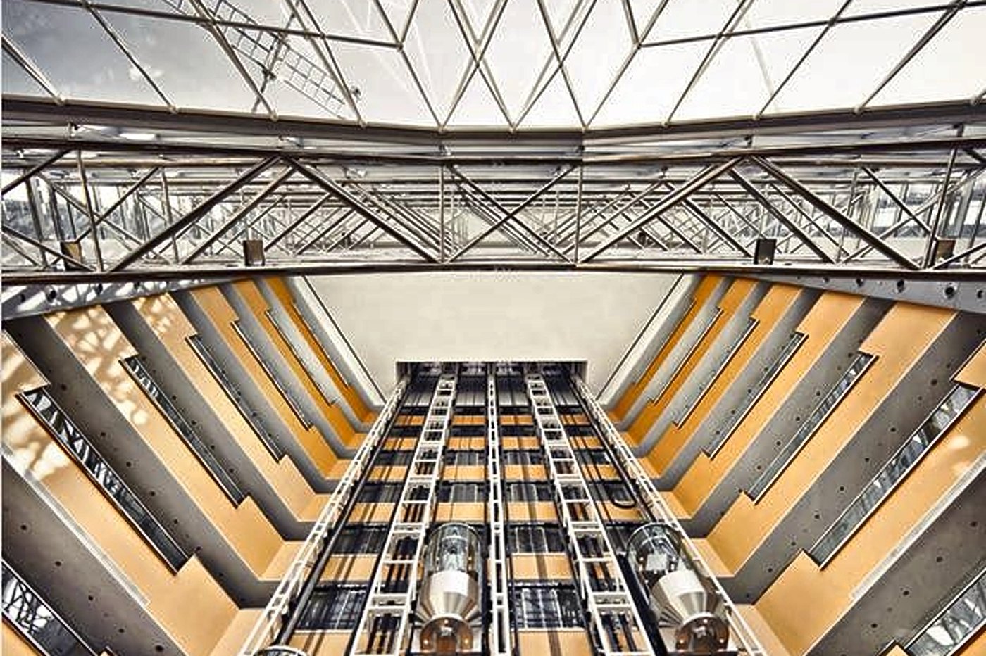 Panoramic glass elevators rising through a naturally lit atrium
